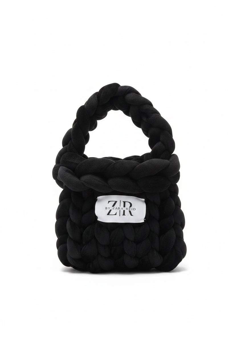 Black chunky braided knit bag with label on white background