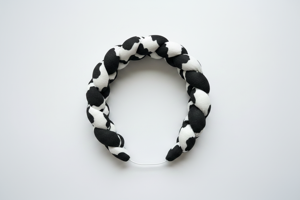 Black and white braided headband flat lay on white background