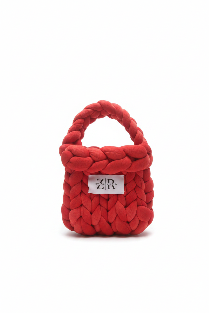 Red chunky braided knit bag with label on white background