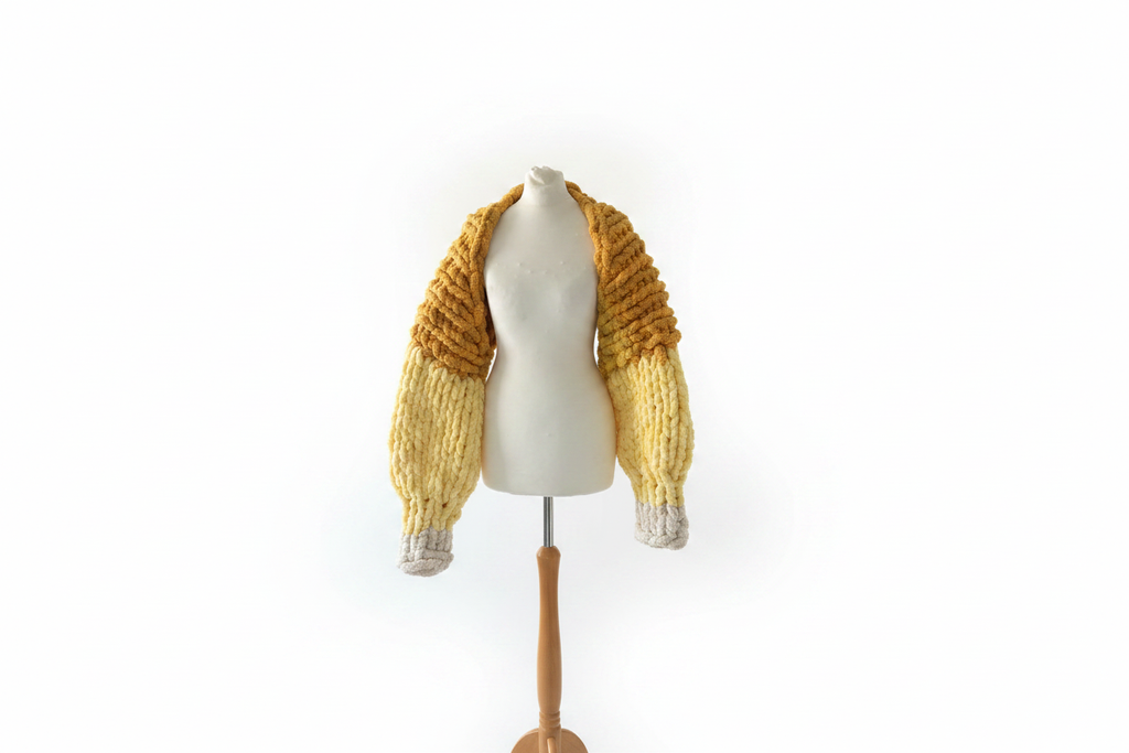 Mustard yellow chunky hand-knit open cardigan on mannequin with white background