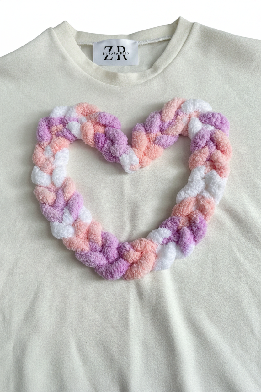 Close-up detail of pastel braided chenille heart appliqué on white tee